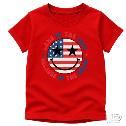 Land of the Free Because of the Braves Patriotic Smiley Face Shirt | American Flag Happy Face Tee | Fourth of July Graphic T-Shirt | USA Independence Day Shirt