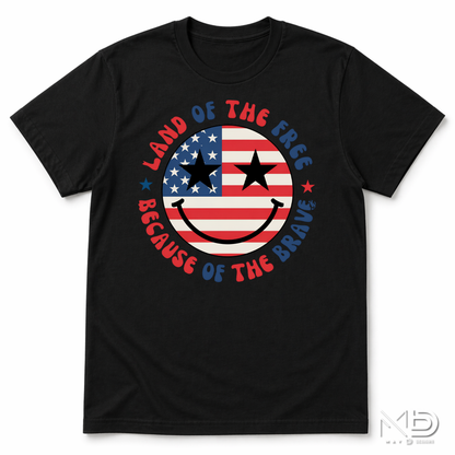 Land of the Free Because of the Braves Patriotic Smiley Face Shirt | American Flag Happy Face Tee | Fourth of July Graphic T-Shirt | USA Independence Day Shirt