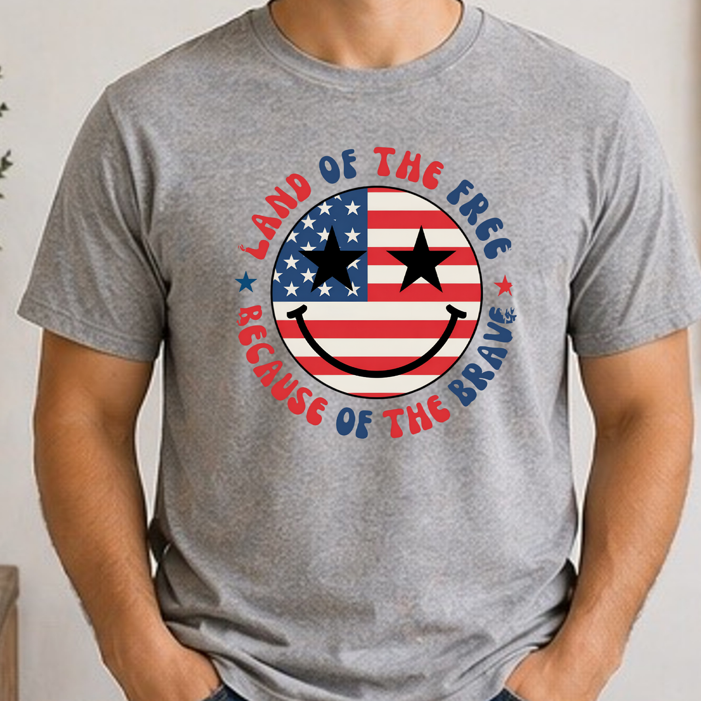 Land of the Free Because of the Braves Patriotic Smiley Face Shirt | American Flag Happy Face Tee | Fourth of July Graphic T-Shirt | USA Independence Day Shirt